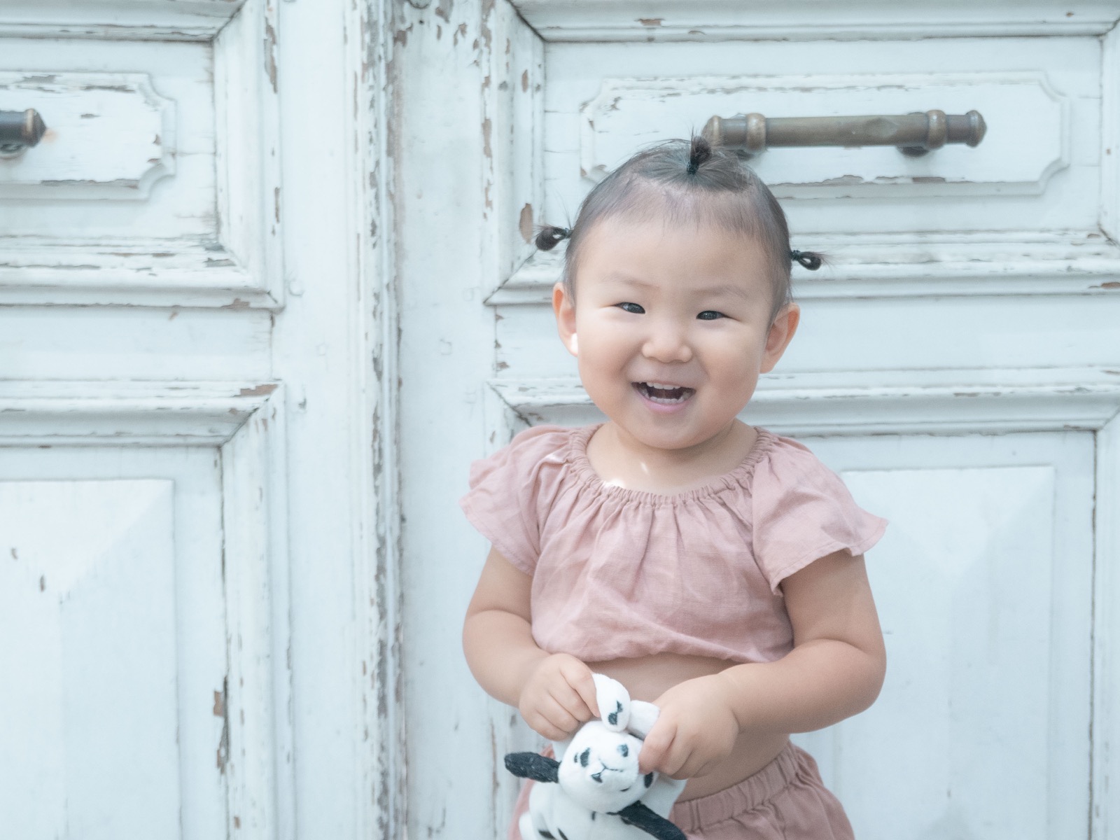 アンティークな白い扉の前で微笑む女の子のポートレート